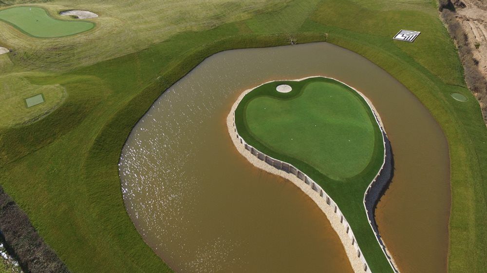 Pittsburgh Aerial view of a vibrant green synthetic grass island in a natural pond on a golf course